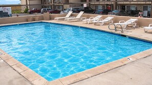 A rectangular pool with clear blue water, surrounded by beige tiles and a concrete deck.
