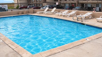 Una piscina rectangular con agua azul cristalina, rodeada de baldosas color beige y una plataforma de hormigón.