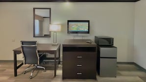 Une chambre d’hôtel équipée d’un bureau, d’une chaise, d’une télévision, d’une lampe et d’un petit réfrigérateur.