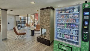 A modern indoor space with a vending machine, seating area, and a stone wall. - Discovery Inn (Midvale)