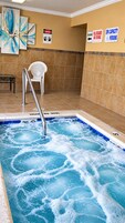 A spa area with a hot tub, safety signs, and a white chair.