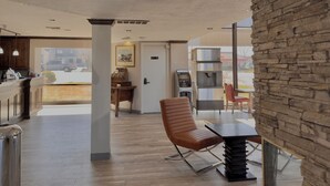 A modern interior with a stone accent wall, a seating area with a table, a water dispenser, and a view of the outside. - Discovery Inn (Midvale)