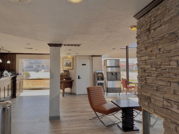 Um interior moderno com parede de destaque em pedra, área de estar com mesa, dispensador de água e vista para o exterior.