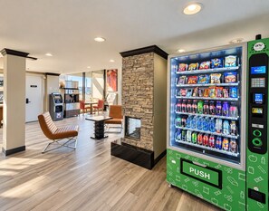 A modern interior with a vending machine, a stone fireplace, and a seating area with a view.