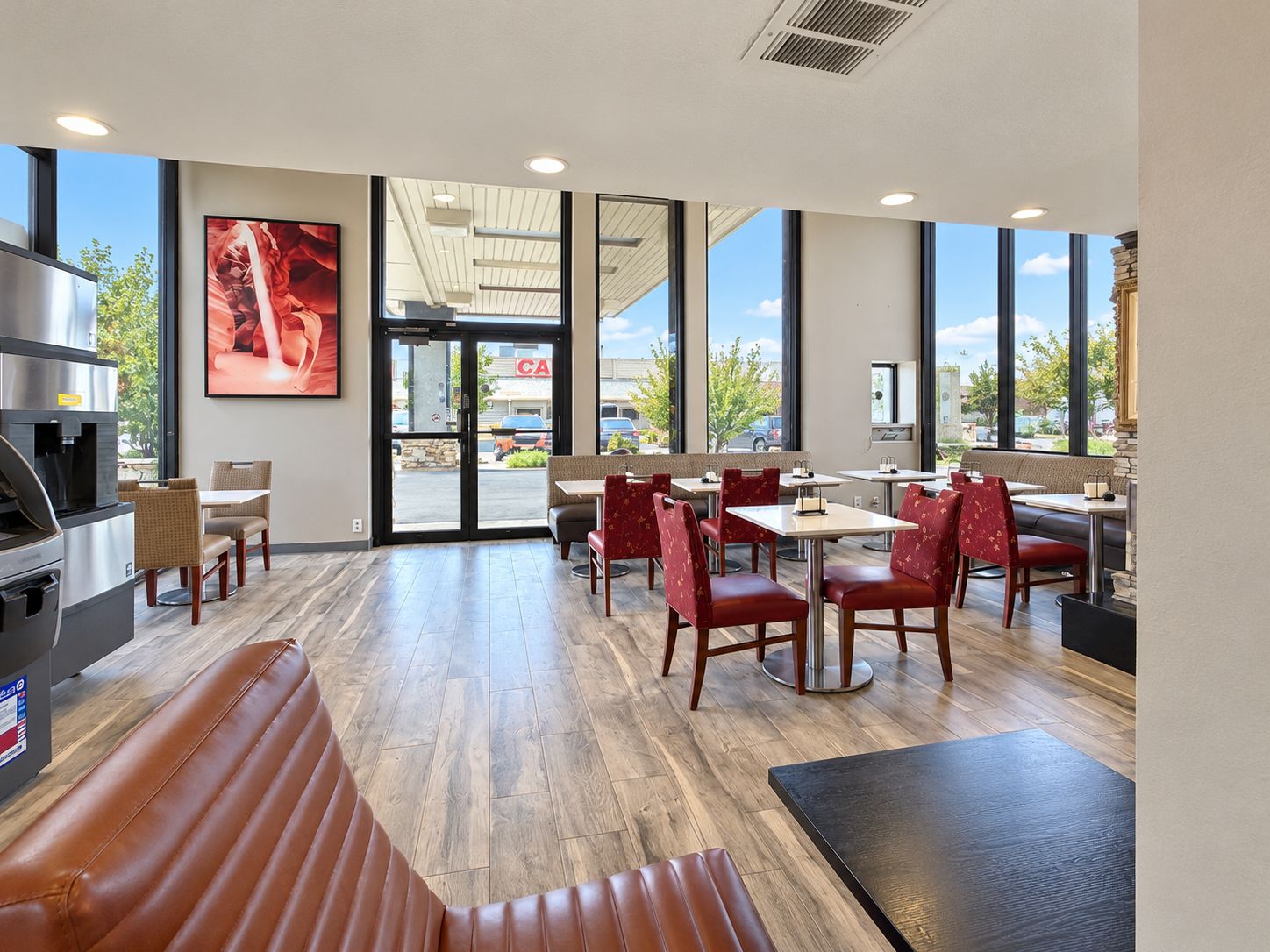 A restaurant interior with a bar area, seating, and a large window offering a view of the street.