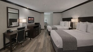 A hotel room with two beds, a desk, a TV, and a mirror. - Discovery Inn (Midvale)