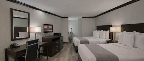 A hotel room with two beds, a desk, a TV, and a mirror.