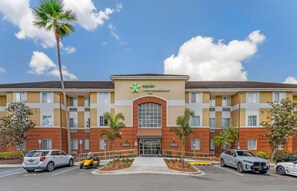 Un hotel StayAmerica con ingresso centrale, parcheggio e palme.