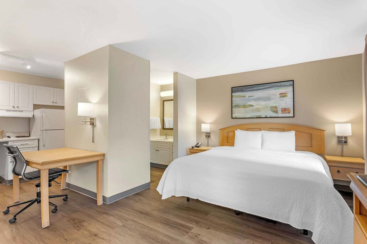 A hotel room with a bed, desk, chair, and a television.