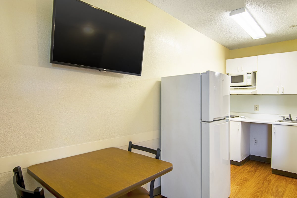Una cocina compacta con refrigerador, microondas y gabinetes blancos.