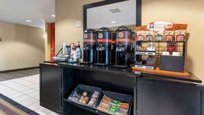 Una estación de café con varias máquinas de café, una exhibición de paquetes de café, y una variedad de bocadillos y pan.