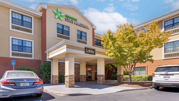 Un hotel con un letrero que dice 'Lobby', un estacionamiento y un árbol en la entrada.