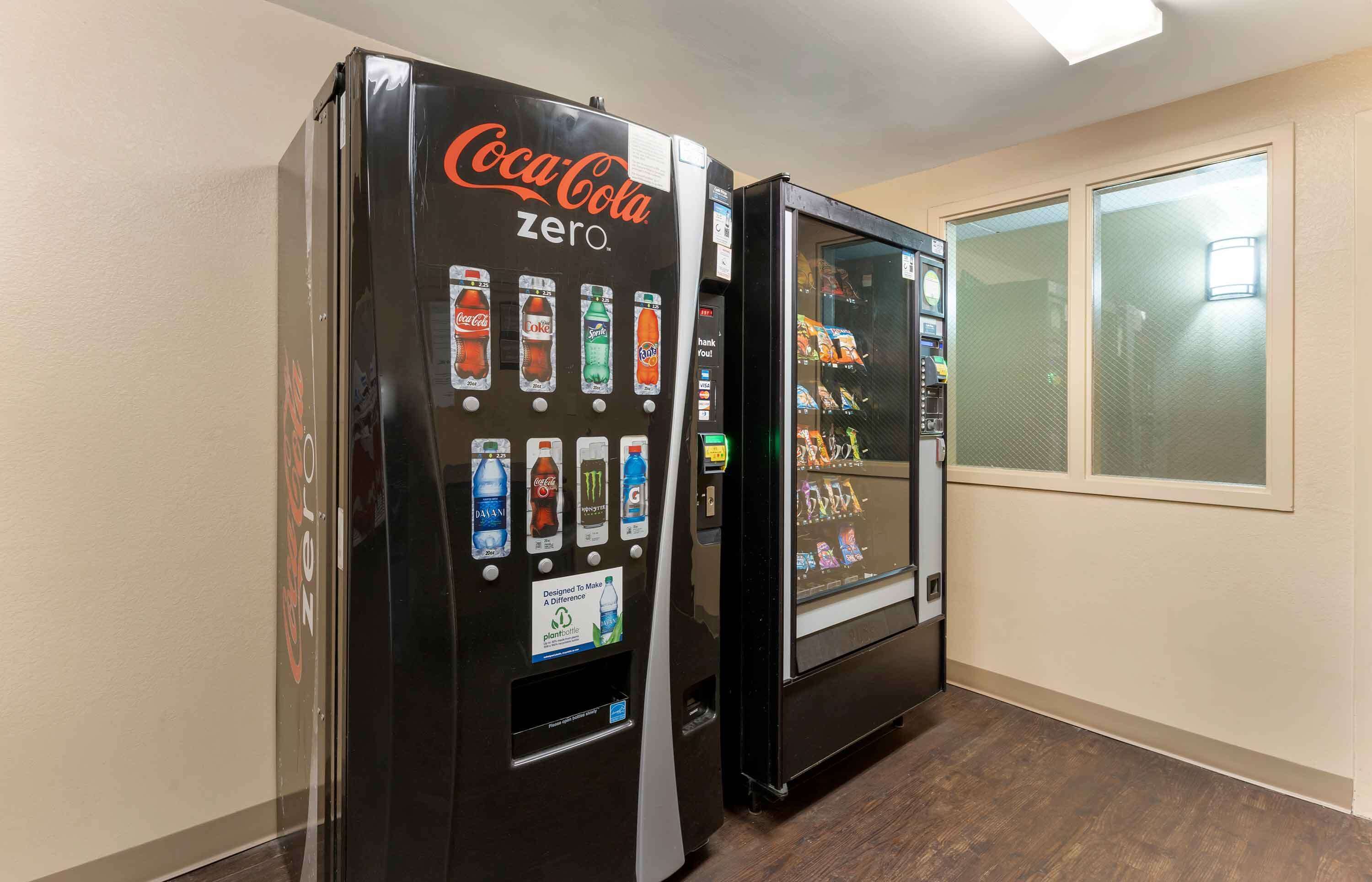 Two Coca-Cola Zero vending machines in a hallway with a window on the right.