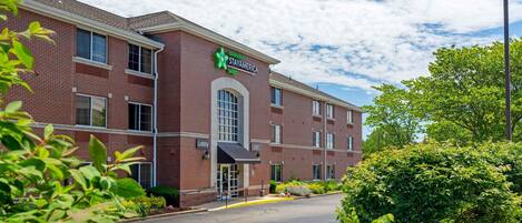 A StayAmerica hotel with a brick facade, a lobby entrance, and a parking lot.