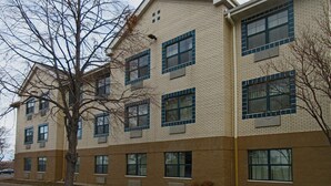 A multi-story building with a brick facade, large windows, and a tree in front. - Suburban Studios Minneapolis Bloomington (Bloomington)
