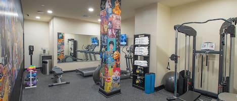 A gym with exercise equipment, a mirrored wall, and a colorful poster.