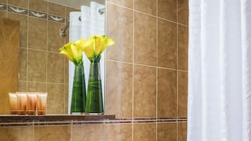 Kylpyhuoneessa on pesuallas, peili ja wc-istuin. Tasolla on kaksi vaasia, joissa on keltaisia kukkia.