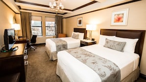 A hotel room with two beds, a desk with a computer, a chair, and a window with a city view. - The Belvedere Hotel (New York)