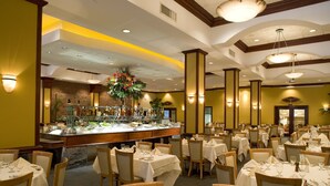 A dining area with multiple tables set for service, a buffet with various food items, and a brick wall in the background. - The Belvedere Hotel (New York)