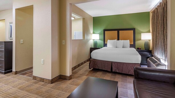 A hotel room with a large bed, a desk, a chair, and a nightstand with lamps. - Extended Stay America Suites San Antonio Colonnade Medical (San Antonio)