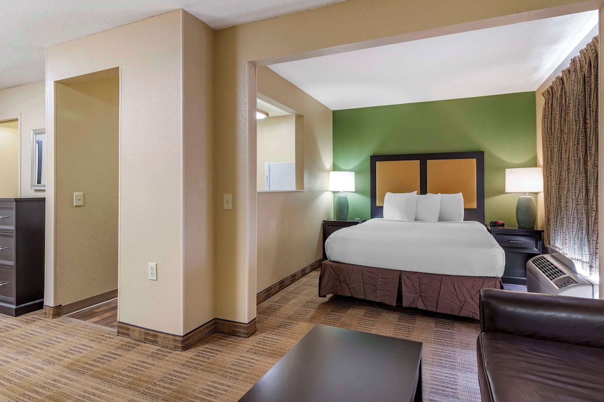 Habitación de hotel con una cama grande, un escritorio, una silla y una mesita de noche con lámparas.