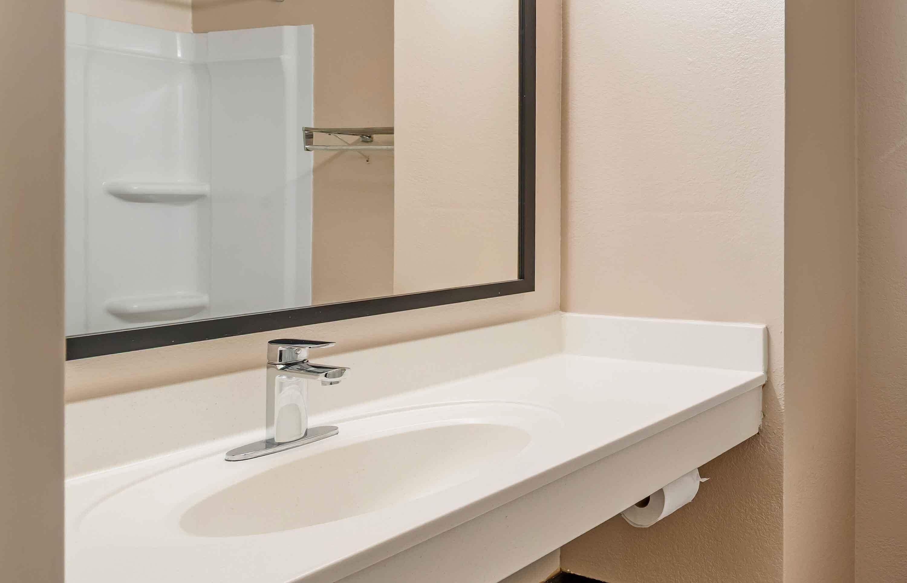 A bathroom with a white sink, a mirror, and a towel rack.