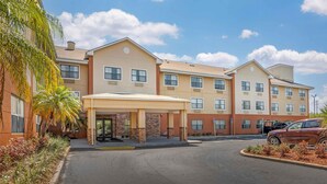 A multi-story hotel with a covered entrance, palm trees, and a parking lot. - Extended Stay America Suites St Petersburg Clearwater ExecDr (Clearwater)