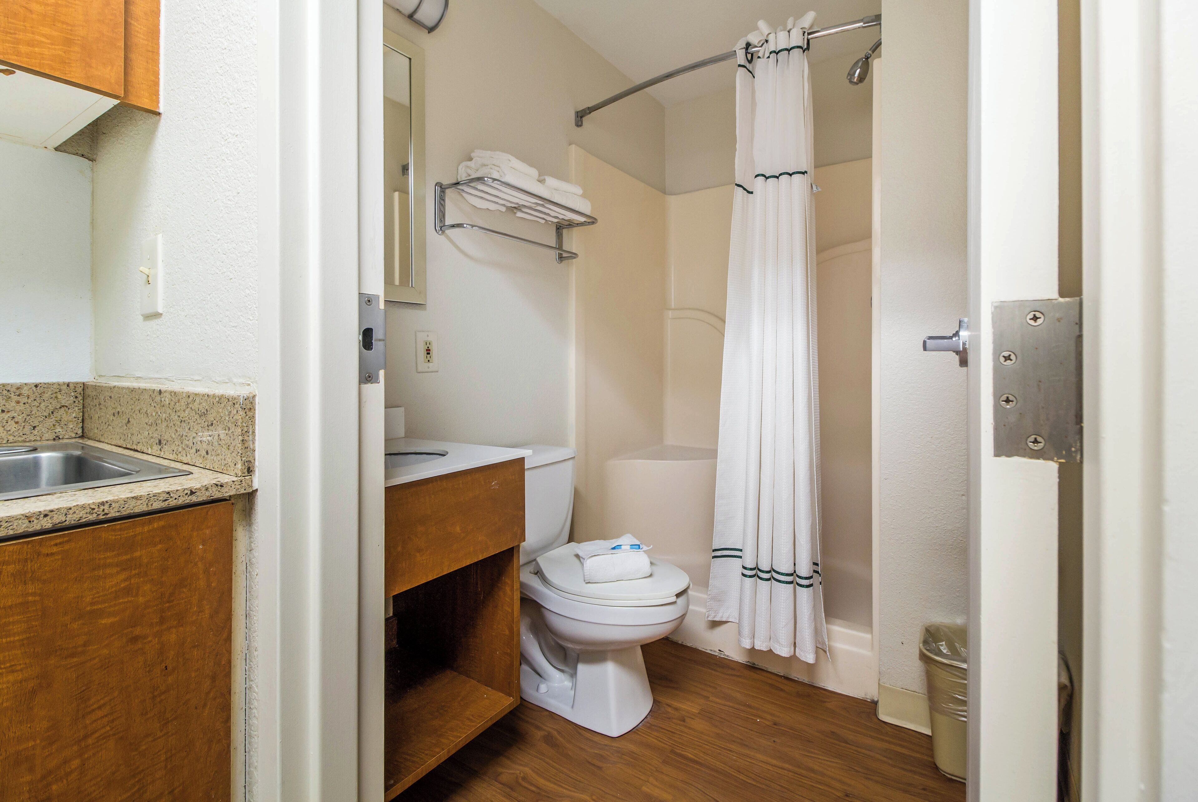 Een badkamer met een wastafel, toilet, douchegordijn en een handdoekhouder.