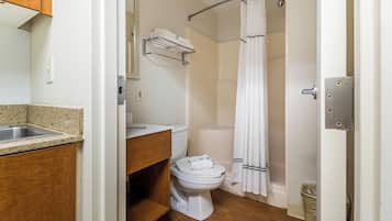 Een badkamer met een wastafel, toilet, douchegordijn en een handdoekhouder.