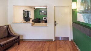 A reception area with a reception desk, a computer, a printer, and a sign for Home Town Studios. - HomeTowne Studios by Red Roof Houston - Northwest (Houston)