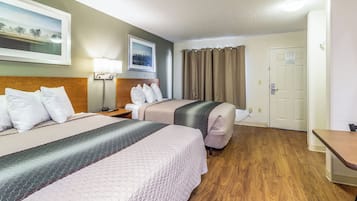 Une chambre d’hôtel avec deux lits, une table de chevet, une lampe, un tableau et une porte.