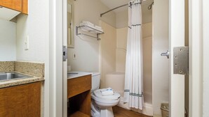 A bathroom with a sink, toilet, and shower curtain. - HomeTowne Studios by Red Roof Houston - Northwest (Houston)