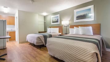 A hotel room with two beds, a desk, and a TV.
