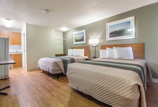 Una habitación de hotel con dos camas, un escritorio y un televisor.
