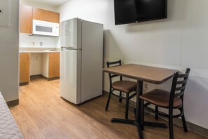 Una cocina compacta con refrigerador, microondas y una mesa de comedor con sillas.