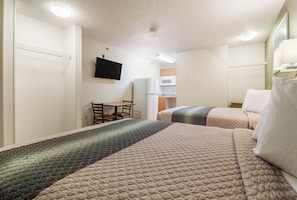 Quarto de hotel com duas camas, uma escrivaninha, televisão e micro-ondas.