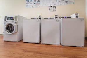 Une buanderie équipée d’un lave-linge à chargement frontal et de trois sèche-linge superposés.