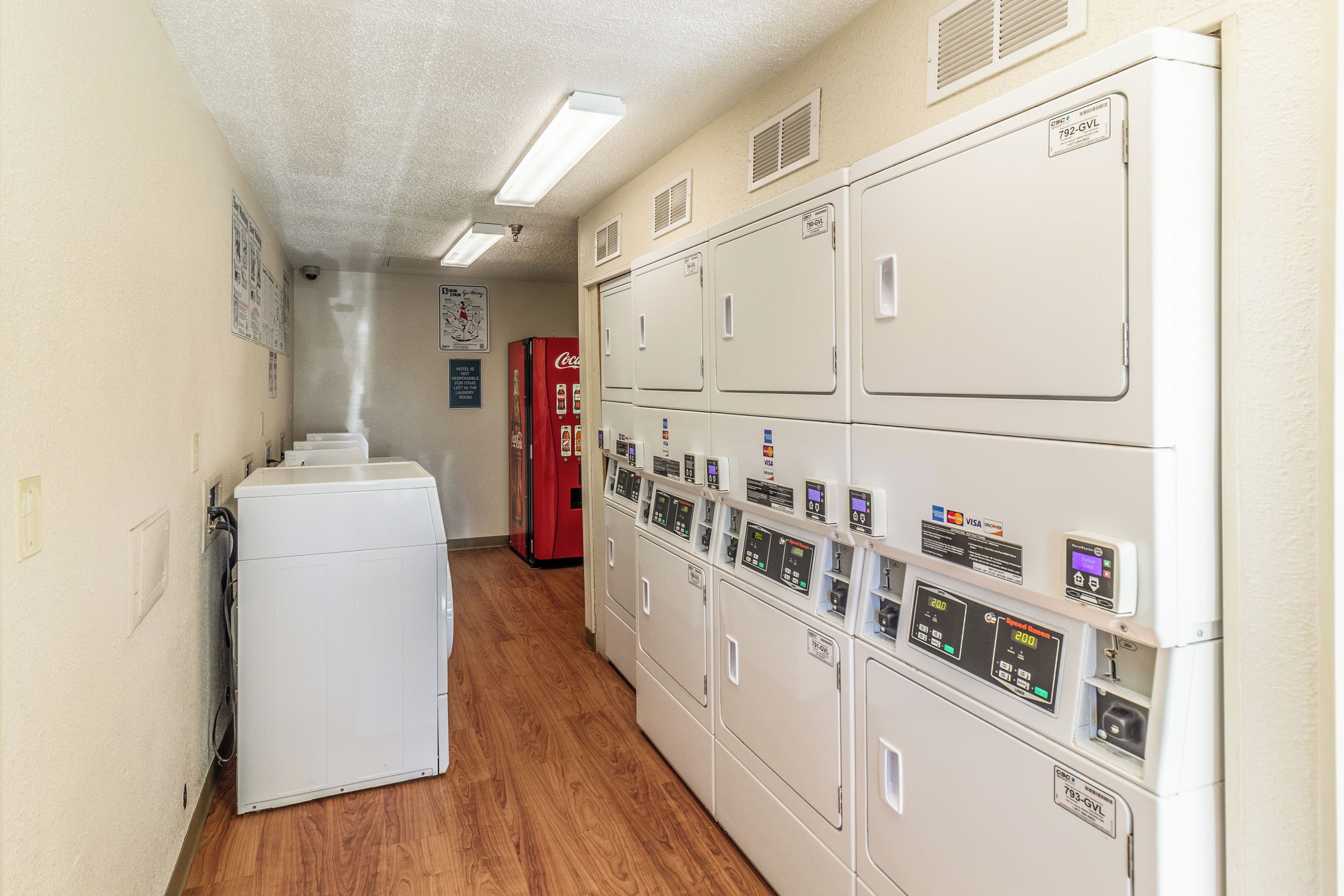 A laundry room with stacked dryers and a red Coca-Cola refrigerator.