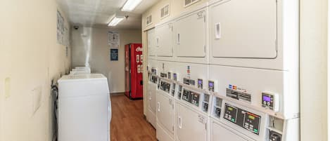 A laundry room with stacked dryers and a red Coca-Cola refrigerator.