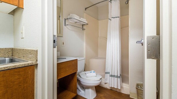 A bathroom with a sink, toilet, and shower curtain. - HomeTowne Studios by Red Roof Houston - Northwest (Houston)
