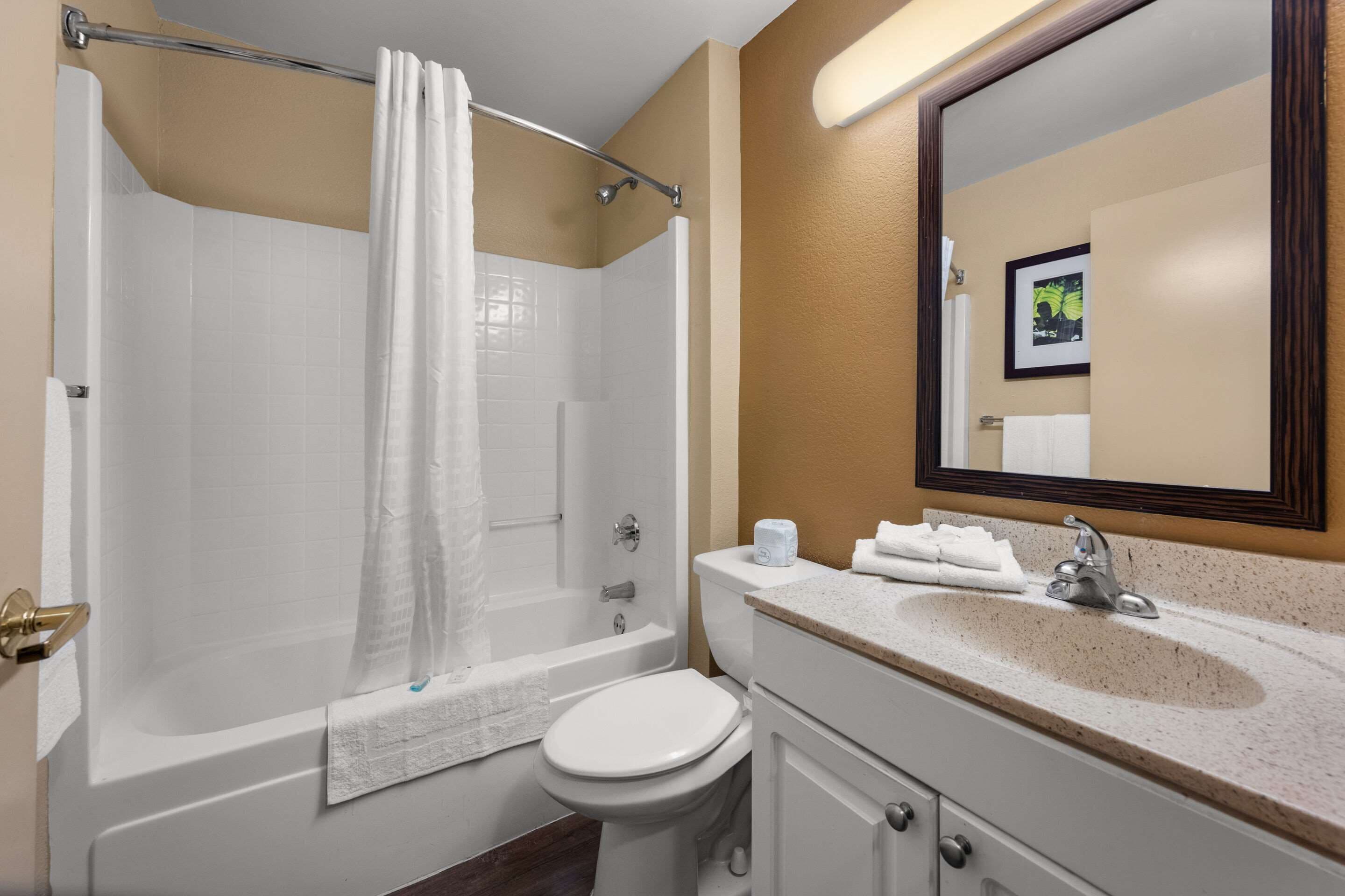 A bathroom with a bathtub, toilet, sink, and a mirror.