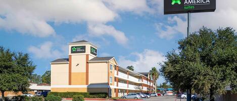 Un hôtel Stay America Suites avec un ciel dégagé, un parking et un bâtiment à plusieurs étages.