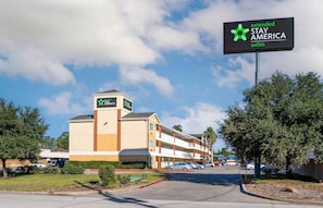 A Stay America Suites hotel with a clear sky, a parking lot, and a building with multiple floors. - Extended Stay America Suites Houston The Woodlands (Spring)