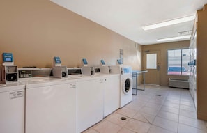 A laundry facility with multiple washing machines and dryers, a control panel, and a window with a view of the outside. - Extended Stay America Suites Houston The Woodlands (Spring)