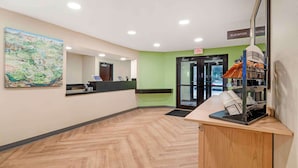 A reception area with a herringbone floor, a reception desk, a large painting, and an elevator sign. - Extended Stay America Suites Asheville Tunnel Rd (Asheville)