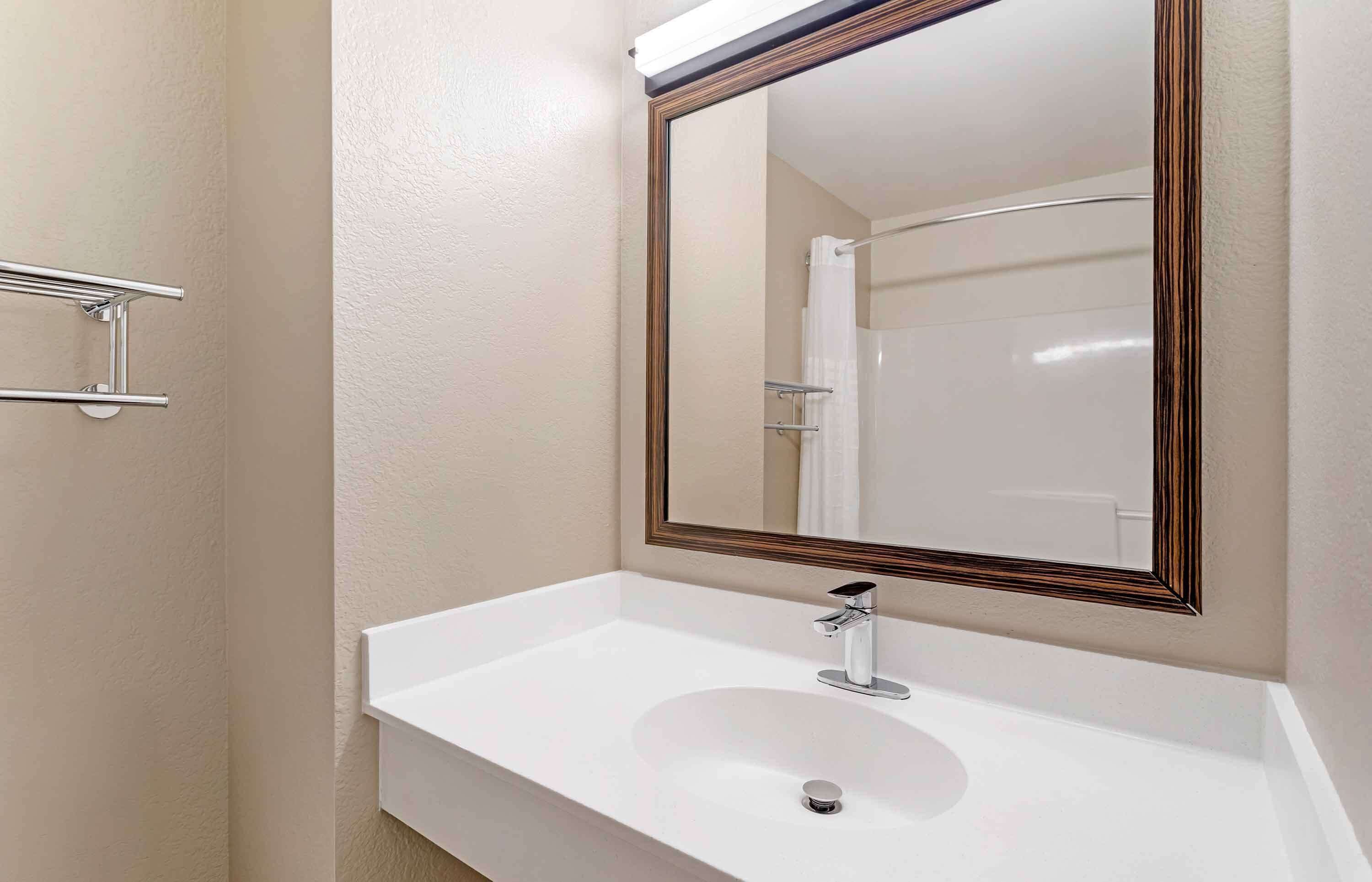 Een badkamer met een witte wastafel, een spiegel met houten lijst en een douchegordijn.