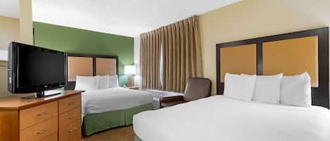 Habitación de hotel con dos camas, televisión, escritorio y una silla.