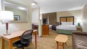 Une chambre d’hôtel avec un lit, un bureau, une chaise et une petite table.