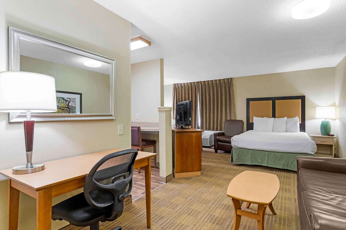A hotel room with a bed, desk, chair, and a small table.