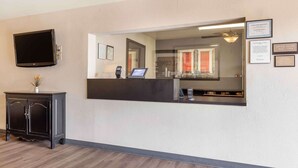 Ein Empfangsbereich mit Flachbildfernseher, einer Rezeption, einem Telefon und gerahmten Zertifikaten an der Wand.